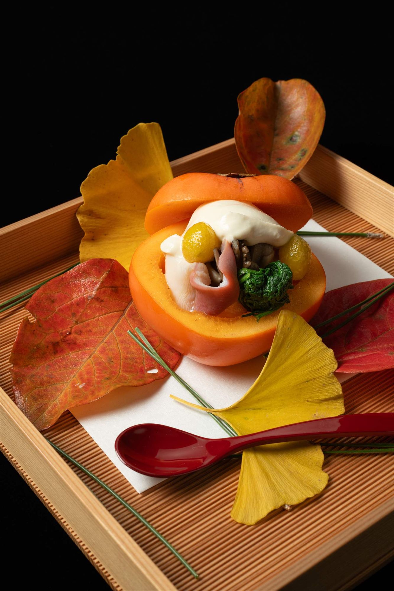 柿の器に盛り付け、紅葉といちょうを添えた秋の前菜